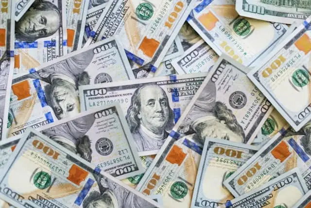 Scattered stack of U.S. one hundred dollar bills, representing cash flow, liquidity, or financial performance.