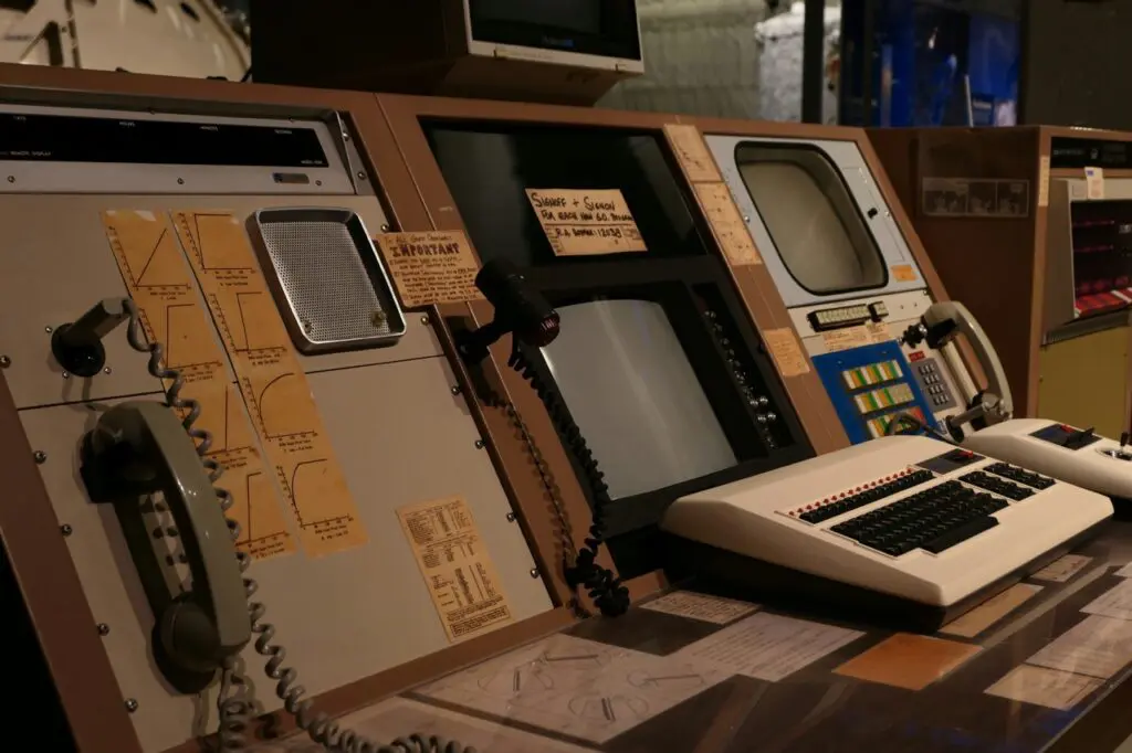 A vintage NASA-style control panel featuring analog telephones, dials, handwritten notes, and early computer monitors, symbolizing the evolution from legacy systems to modern enterprise software for finance.