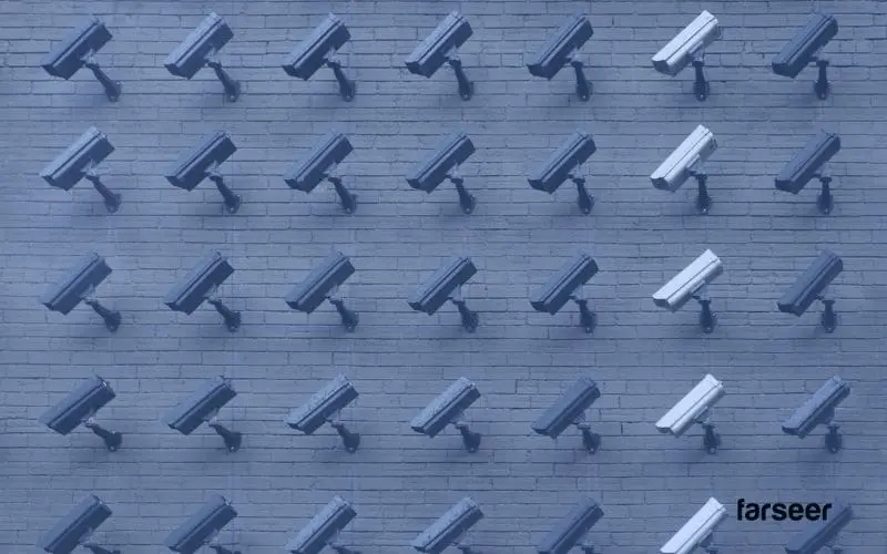 Surveillance cameras aligned on a brick wall, with a few white ones standing out – a metaphor for standardization vs. differentiation in software choices.