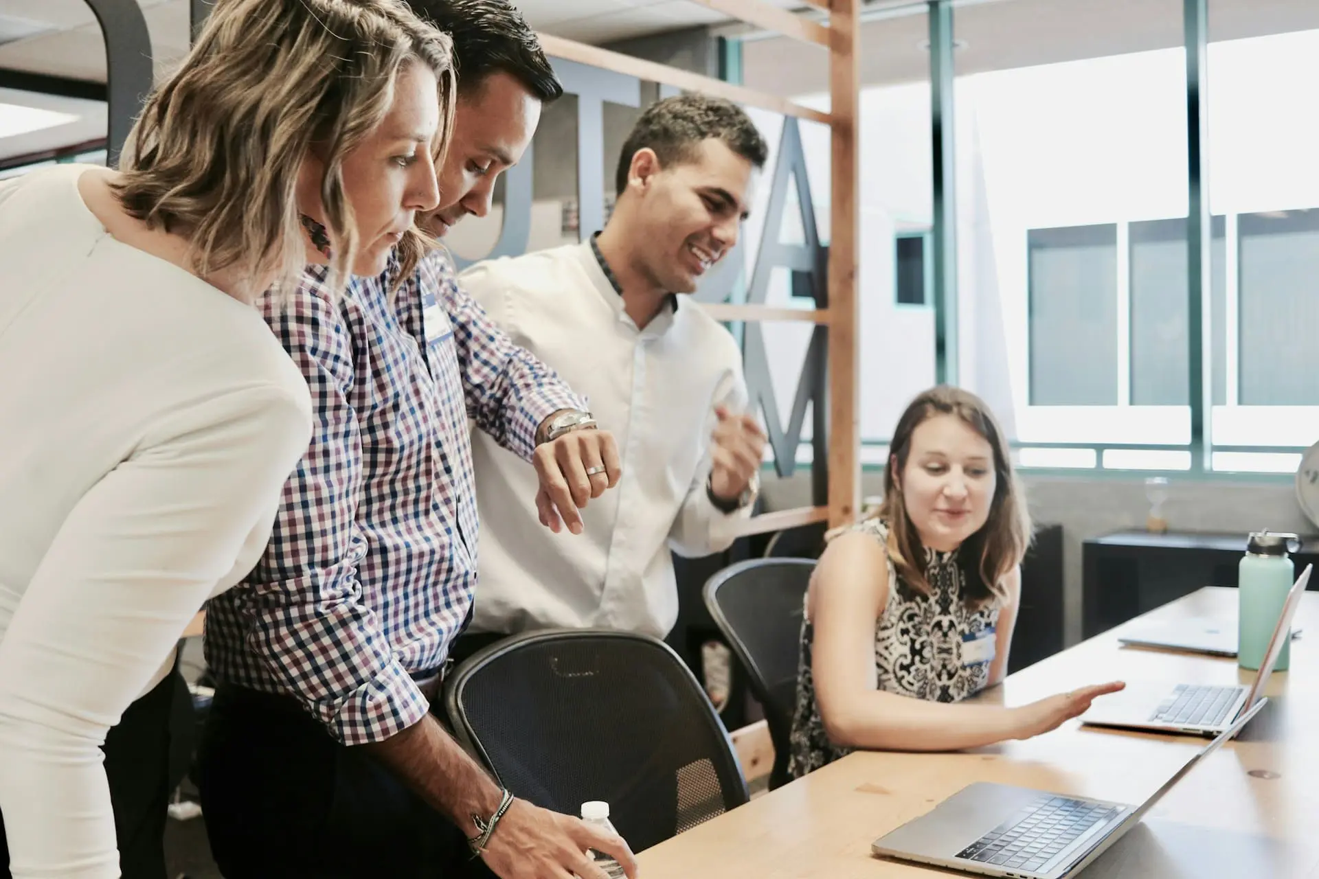 a group of businessmen and businesswomen looking at a laptop screen