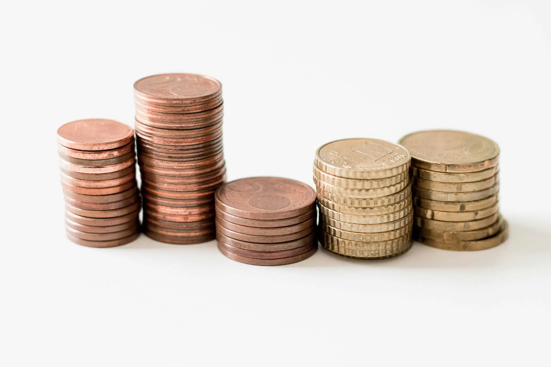 Stacks of assorted euro coins arranged by height on a white surface, representing financial management, cash flow, or working capital.