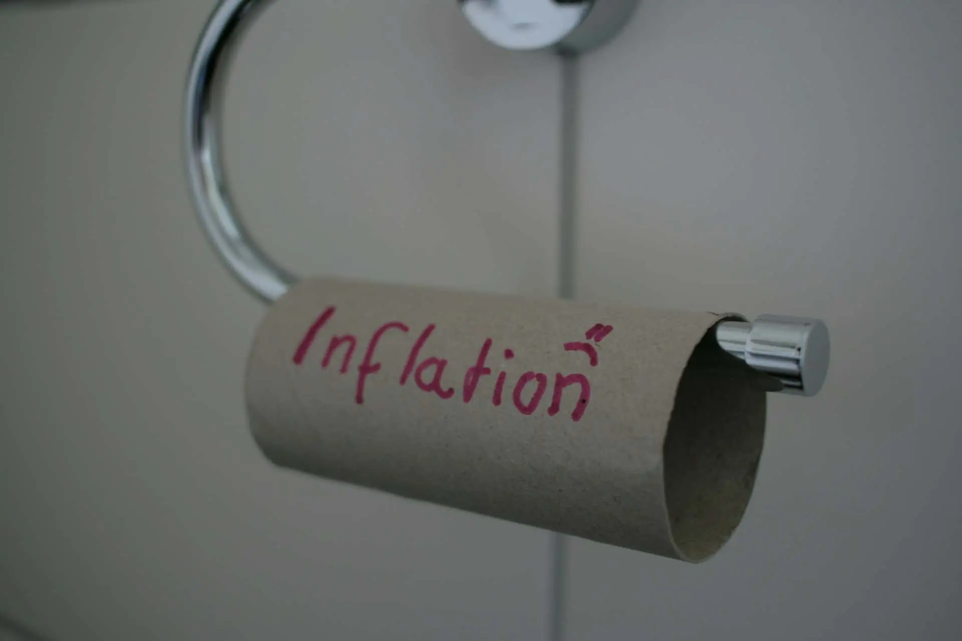 Empty toilet paper roll labeled "Inflation" in red marker, mounted on a silver holder, symbolizing economic shortage or rising prices.