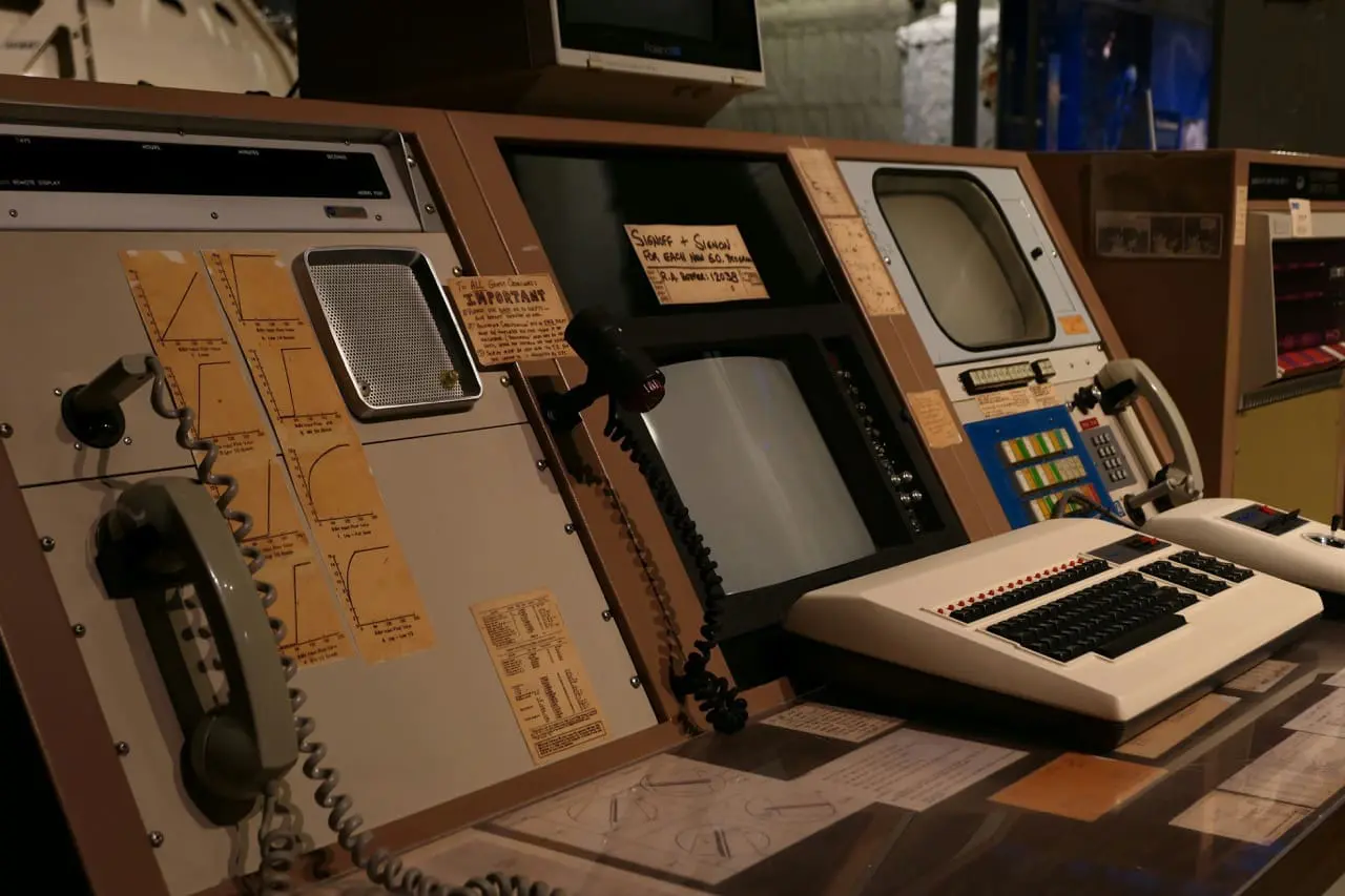 A vintage NASA-style control panel featuring analog telephones, dials, handwritten notes, and early computer monitors, symbolizing the evolution from legacy systems to modern enterprise software for finance.