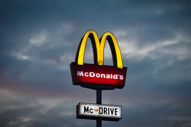 a large McDonald's sign with a cloudy sky background